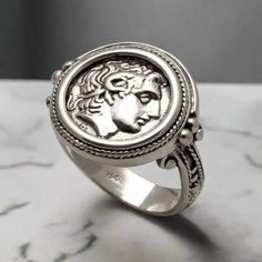 This unique Alexander the Great Portrait Coin Ring in Sterling Silver is perfect for those with a deep appreciation for ancient Greek jewelry. Finely handcrafted, this high-quality ring is the perfect statement piece for the true connoisseur. The entire ring is made of sterling silver.  Sterling Silver Ring the brightest of all precious metals Handcrafted Ring. Forget the standardized jewelry on the market! Stand out with our individually ELEFTHERIOU EL handcrafted Jewelry Greek ring inspired by Macedonian Empire, Ancient Greek Jewelry, Greek Ring, Grand Est, Ancient Coin, Handmade Sterling Silver Rings, Greek Jewelry, Coin Ring, Alexander The Great