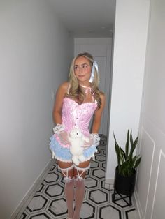 a woman in a pink corset holding a white teddy bear and posing for the camera