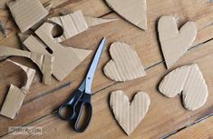 some cut out hearts sitting on top of a wooden table next to a pair of scissors