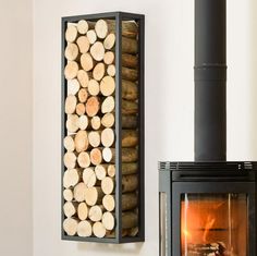 a fire place with logs in it next to a wall mounted wood heater and fireplace