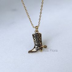 "Step into the allure of the Wild West with this captivating 14k gold dipped dainty antique cowboy boots necklace. Inspired by the timeless beauty of vintage western fashion, this necklace exudes rustic charm and adds a touch of whimsy to any outfit. The intricately designed cowboy boots pendant, crafted with attention to detail, hangs gracefully from a delicate gold chain, creating a unique and stylish accessory. Whether you're a cowgirl at heart or simply appreciate the nostalgia of bygone era Handmade Western Style Gold Jewelry, Handmade Western Gold Jewelry, Handmade Western Style Necklace For Gift, Vintage Gold Jewelry For Rodeo, Western Style Gold Jewelry For Country Events, Western Style Gold Jewelry As Gift, Vintage Handmade Necklace For Western-themed Events, Handmade Vintage Necklace For Western-themed Events, Western Gold Engraved Jewelry