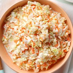 a bowl filled with coleslaw and carrots on top of a white table cloth