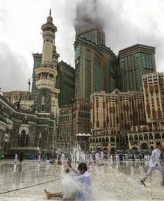 people are playing in the water near some tall buildings and skyscrapers on a cloudy day