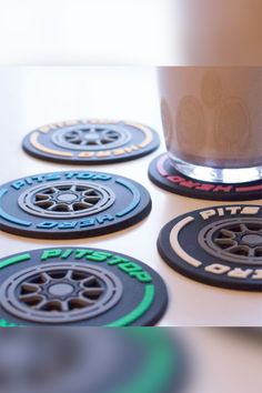 four coasters with black and green designs are on a table next to a cup