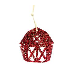 a red cupcake ornament hanging from a white string on a white background