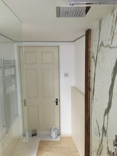 an empty bathroom with marble walls and flooring in the shower area, next to a white door