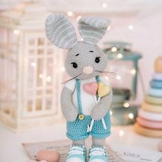 a crocheted bunny holding an ice cream cone in his hand and wearing blue overalls