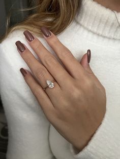 a woman's hand with a diamond ring on her left hand, wearing a white sweater