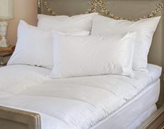 a bed with white pillows on top of it and a headboard in the background