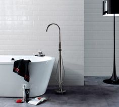 a white bath tub sitting next to a black lamp