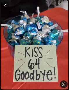 a glass bowl filled with blue and silver candies next to a sign that says kiss got goodbye