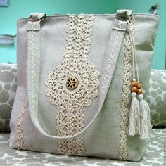 a white purse sitting on top of a bed next to a pillow and wall hanging