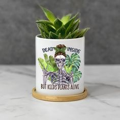 a plant in a white ceramic pot with the words dead inside but kids plants alive on it