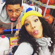 a man sticking out his tongue next to a woman in a grocery cart at a store