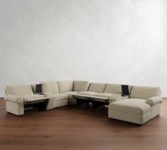 a large sectional couch sitting on top of a hard wood floor next to a white wall