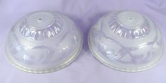 two clear dishes sitting on top of a purple cloth