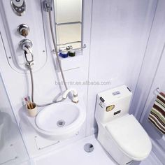 a bathroom with a toilet, sink and shower head mounted to the side of the wall