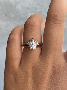 a woman's hand with a diamond ring on top of her finger, showing the center stone