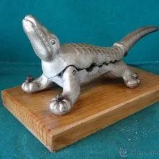 a small metal alligator sitting on top of a wooden board