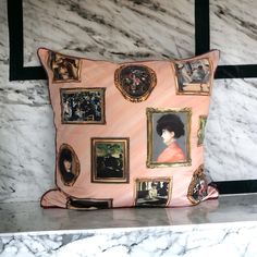 a pink pillow with pictures on it sitting on top of a marble counter next to a window