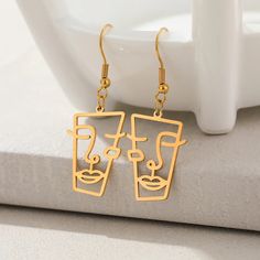 Abstract Face Gold Dangle Drop Earrings Modern Gold Linear Earrings For Gift, Modern Gold-plated Linear Earrings With Ear Wire, Modern Gold Plated Linear Earrings With Ear Wire, Modern Gold Plated Earrings For Gift, Modern Gold-plated Earrings As Gift, Modern Gold-tone Drop Linear Earrings, Modern Metal Jewelry With Artistic Design, Minimalist Gold-tone Earrings For Gift, Minimalist Gold-tone Earrings As Gift