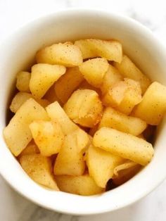 a white bowl filled with sliced apples on top of a table