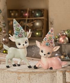 two little deer figurines sitting next to each other on top of a shelf