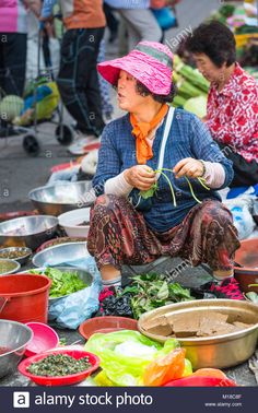 a woman sitting on the ground in front of many bowls with vegetables and other items