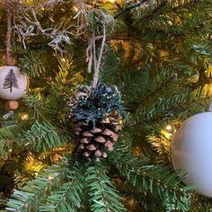 christmas ornaments hanging from a tree with pine cones and balls on it's branches