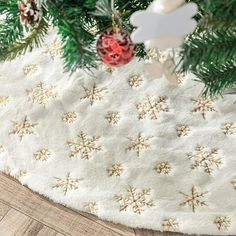 a christmas tree skirt with snowflakes and ornaments hanging from it's sides