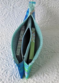 an open zippered purse sitting on top of a white bed covered in quilts