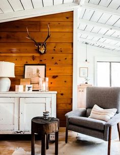 a living room with wood paneling and a deer's head on the wall