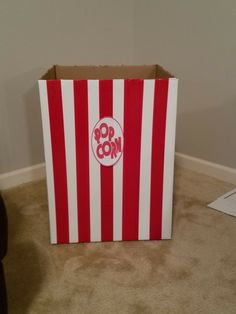 a red and white striped box sitting on top of a carpeted floor next to a wall