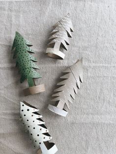 paper christmas trees are arranged on a sheet of white fabric with holes in the middle