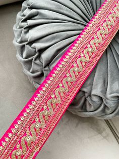 a pink and gold sash sitting on top of a gray pillow