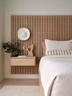 a white bed sitting next to a wooden headboard with a plant on top of it