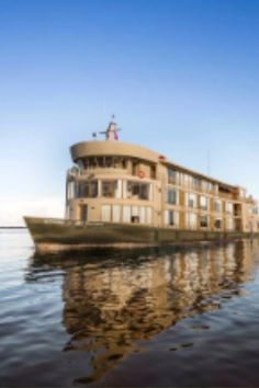 a large boat floating on top of a lake next to a tall wooden structure with windows