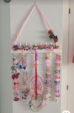 a mobile is hanging on the wall with many bracelets and beads attached to it