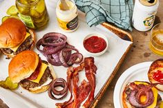 a table topped with burgers, pickles and onion rings