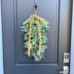 a wreath hanging on the front door of a house with yellow ribbon tied around it