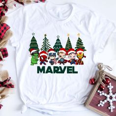 a white shirt with the words marvel and christmas trees on it, next to some other items