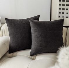 two black pillows sitting on top of a white couch