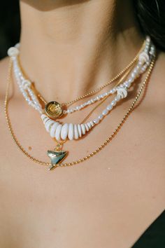 a woman wearing three different necklaces with shells and starfish charms on her neck