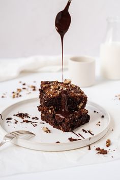 a piece of brownie on a plate with chocolate sauce drizzled over it