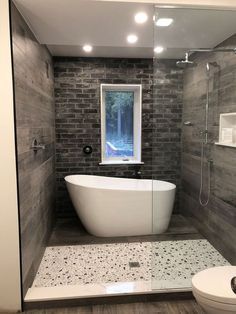 a white bath tub sitting inside of a bathroom next to a toilet and shower stall