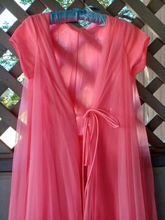 A beautiful bright pink robe by Lucie Ann Beverly Hills. It is all nylon, made of a layer of sheer chiffon over soft opaque nylon. This piece has ties in the front, but no pompoms. I believe this was the original design, as the ties do not look like they were cut. There is a nylon belt inside the robe as well. The robe is made of yards of fabric, giving it a gorgeous wide sweep.  Bust - 34" (86 cm) Waist - 38" (96 cm) Hips - Open Sleeves - 4.5" (11 cm) Length - 53" (134 cm) This piece appears to be in very good condition. There are some small picks in the chiffon, and a small stain (8th photo). I can't remember where the stain is located exactly on the robe. Though I think it may be somewhere on the skirt. This should fit a modern Small to Medium. This piece will be very long on petite fig Sewing Projects Clothes, Open Sleeves, Hip Openers, Pink Chiffon, Open Sleeve, 60s Mod, Womens Robes, Sheer Chiffon, Bright Pink