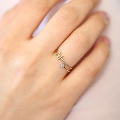 a woman's hand wearing a gold ring with two small diamonds on the band