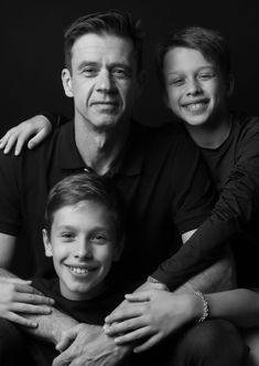 a man and two boys posing for a black and white photo with their arms around each other