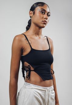 ArtcareShop's new take on a cut out top.  *Side cuts with strings to tie *Spagetti straps  *Petite fit (the model is wearing a size M). Size S Petite - chest 31.9in, length 16.5in Size M Petite - chest 33.4in, length 16.9 in Size L Petite - chest 34.9in, length 17.3in Size XL Petite - chest 36.4in, length 17.7in  Our favorite black  95% cotton and 5% polyester thick fabric (the same as our oversized t-shirts, biker shorts sets and Kai open back turtleneck). The model is wearing a size Petite M. ---------------------------------- ArtcareShop is a women-owned streetwear brand. From street to seam, we seamlessly blend edgy athleisure streetwear with luxurious designer quality to offer you a truly unique and effortless wardrobe that empowers you. Why Choose Us? * Crafted with Love: ArtcareShop Edgy Strappy Tops For Summer, Edgy Summer Tops With Straps, Fitted Tops With Multiple Straps, Black Cotton Top With Tie Straps, Black Cotton Tops With Tie Straps, Black Cotton Tie Back Top, Fitted Top With Multiple Tank Straps, Strappy Tops With Tie Straps For Spring, Spring Strappy Top With Tie Straps