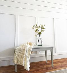 a vase filled with flowers sitting on top of a table next to a white wall